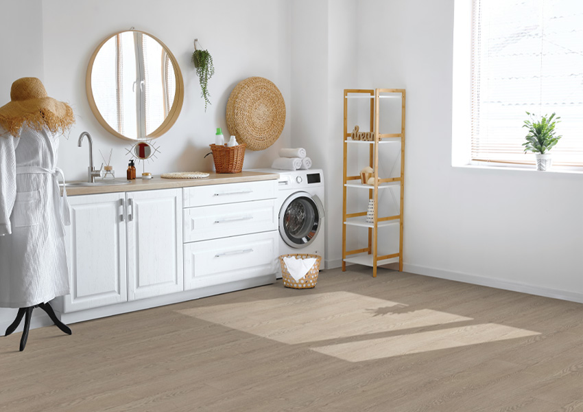 laminate flooring in laundry room with washer and white cabinets.
